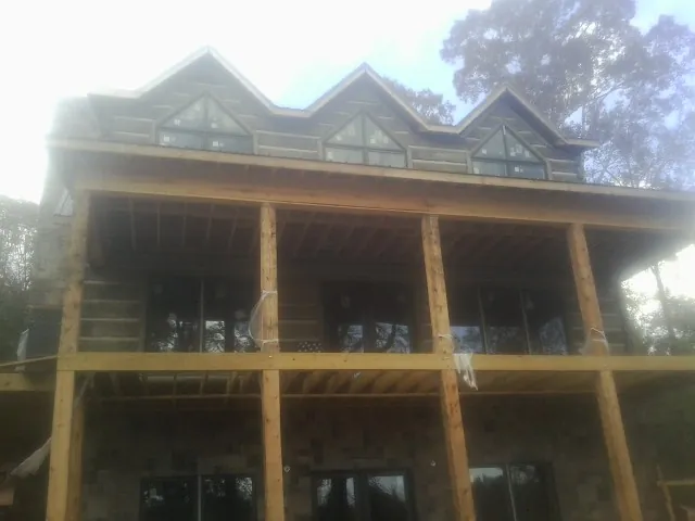 Dormers and porch framing on a large log home under construction — Roof Coating work by our crew in Henning