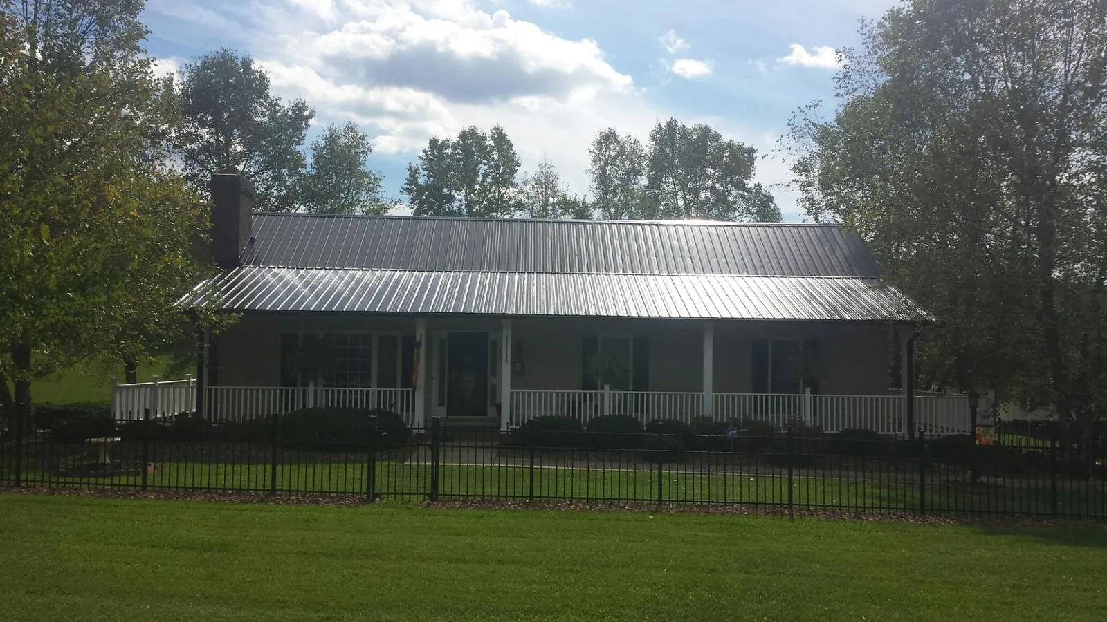 Gray metal roof on a brick ranch with a full width front porch — Gutter Guard Installation work by our crew in Henning