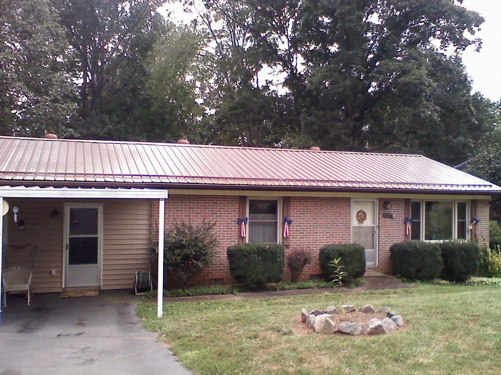 Bronze metal roof and carport on a brick ranch home — Roof Repair work by our crew in Henning